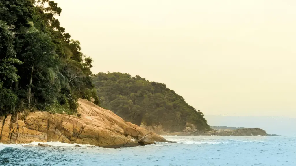 **A Lenda da Praia do Éden: Mitos e Encantos de Um Paraíso Escondido**A Praia do Éden carrega uma aura misteriosa que encanta moradores e visitantes do Guarujá, com histórias que ajudam a explicar o charme e o nome deste refúgio paradisíaco. A versão mais conhecida da lenda sugere que a praia foi batizada como "Éden" por sua paisagem deslumbrante, comparada ao Jardim do Éden descrito na Bíblia – um lugar de perfeição, harmonia e beleza intocada. Essa ideia de um "Éden perdido" traduz a sensação de isolamento e conexão com a natureza que a praia oferece.Outro ponto curioso é que, no passado, a Praia do Éden era frequentada por grupos que buscavam uma ligação mais direta com a natureza, como os naturistas. Essa atmosfera exclusiva e o clima de refúgio contribuíram para a fama do local como um "paraíso secreto", conhecido apenas por quem descobria a trilha até lá.Embora não existam registros históricos precisos sobre a origem dessa lenda, o nome reflete perfeitamente o que a praia representa: um lugar único, ideal para quem deseja se desconectar da correria e mergulhar em um ambiente natural e tranquilo.