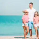 Homem e duas crianças na praia, em pé representando Presentes para pais que amam praia